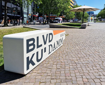 Ławki z betonu architektonicznego z siedziskamia pomalowanymi na kolor z palety RAL.